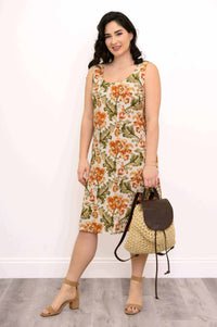 Woman in a floral sleeveless dress holding a woven straw backpack