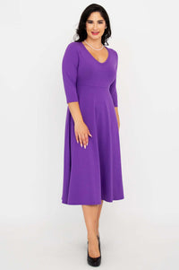 Woman in a purple midi dress posing with hand on hip, displaying the empire waist
