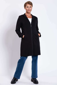 Woman in black Tracy Coat with hands in pockets and slight pose