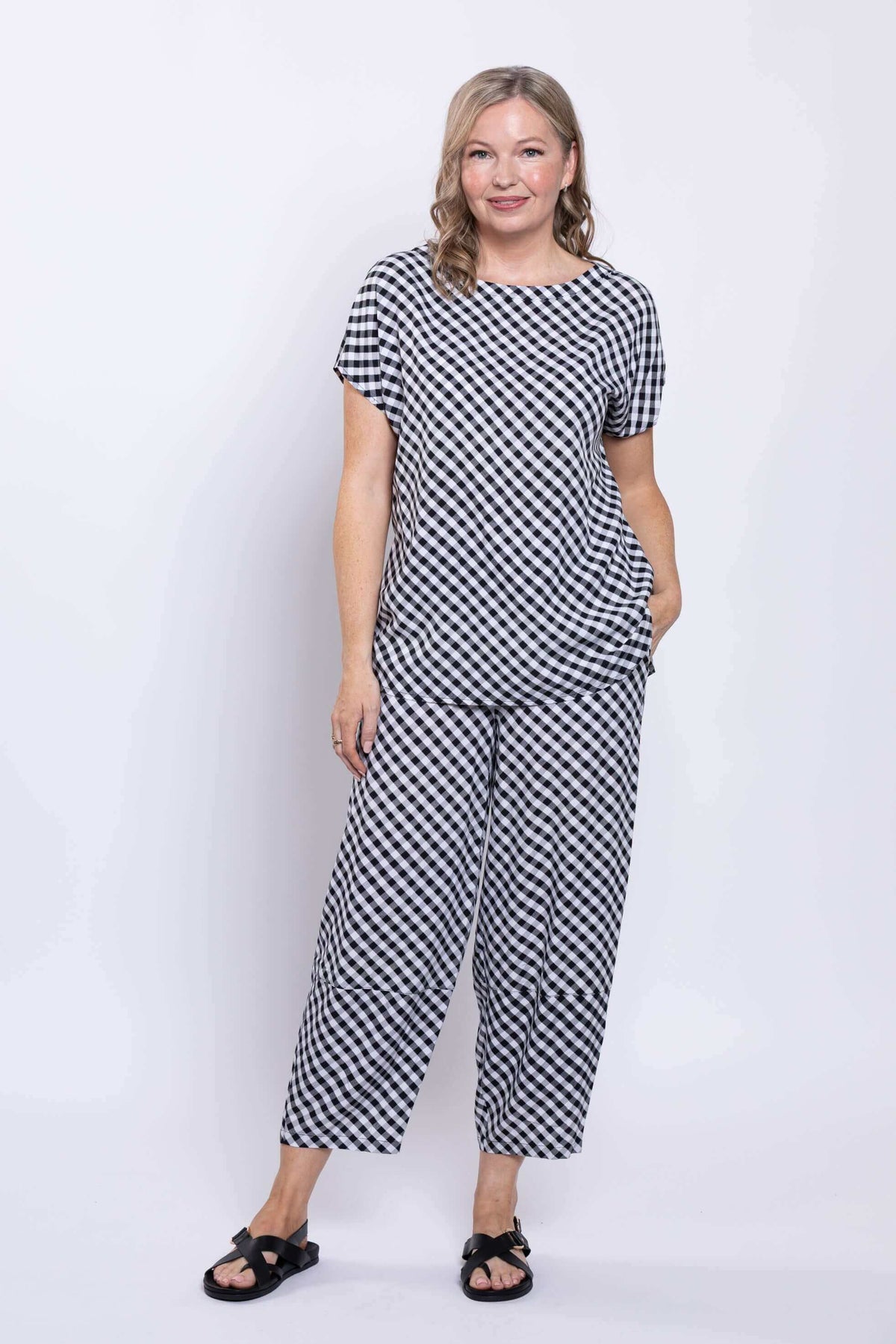 Woman standing in black and white gingham tee and pants, hands in pockets