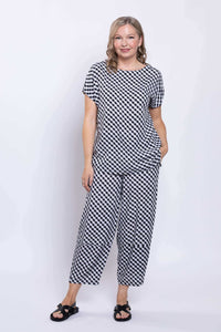 Woman standing in black and white gingham tee and pants, hands in pockets