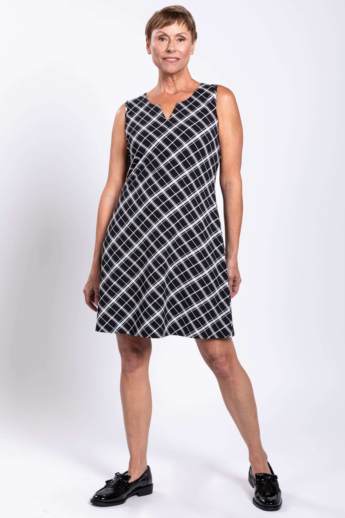 Woman posing in black and white plaid sleeveless shift dress, facing forward