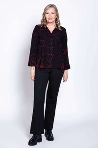 Standing woman in black blouse with maroon abstract patterns and black trousers