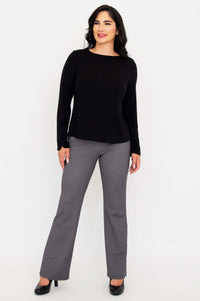 Smiling woman in black boat neck top and gray check pants, hands at sides