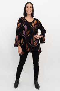 Woman posing with hand on hip, modeling a flowy black top with purple and orange leaf print
