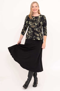 Woman showing the flow of a black maxi skirt with a black brushstroke top