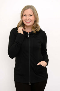 Woman smiling and wearing a black fitted hoodie jacket with pockets