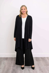 Woman in black high-low hem duster cardigan over white top, facing forward