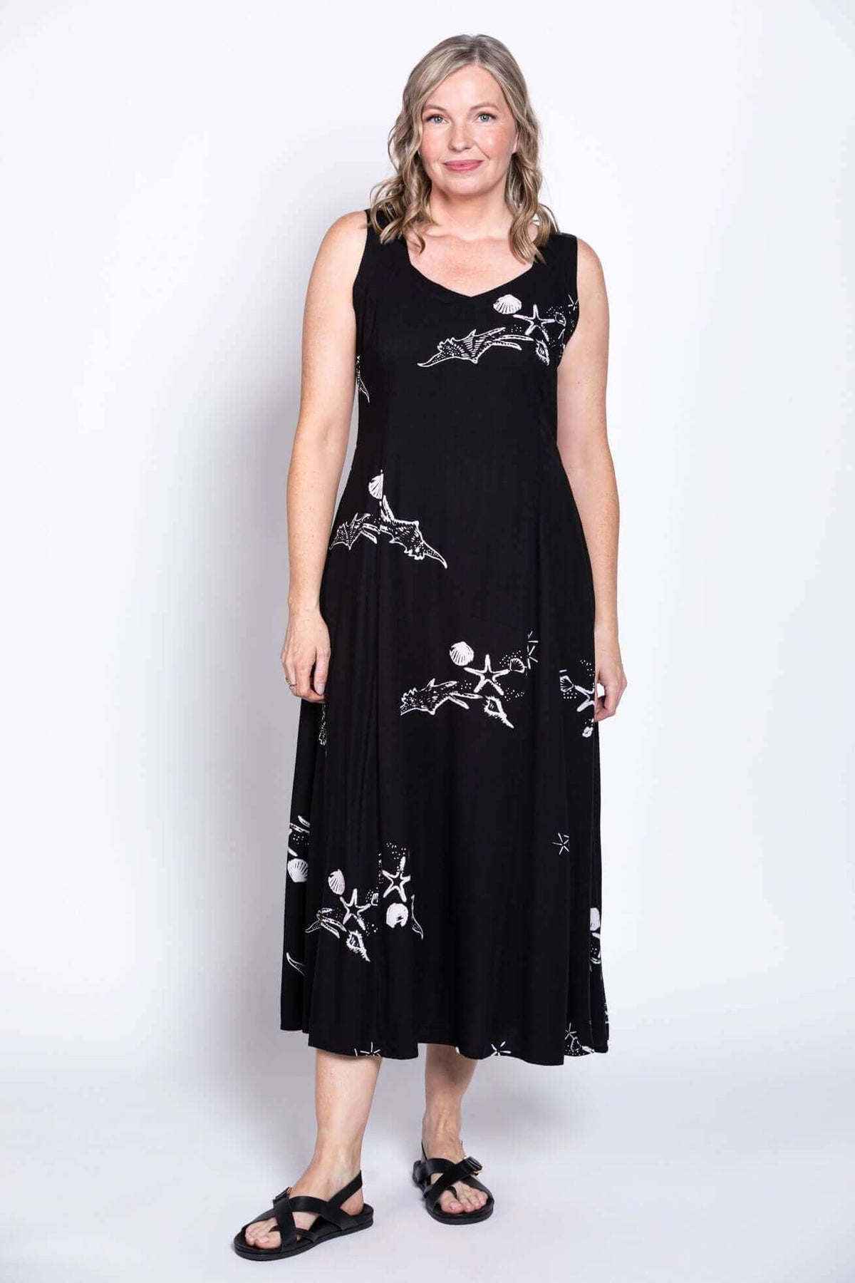 Woman wearing a black sleeveless A-line dress with white nature-inspired prints