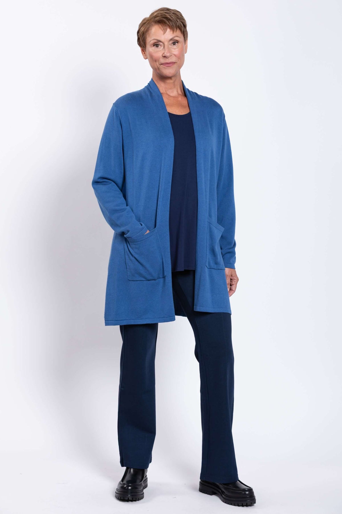 Woman wearing blue Paige cardigan, standing with hand in pocket