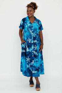 Woman in blue batik A-line dress with pockets, standing against a white background