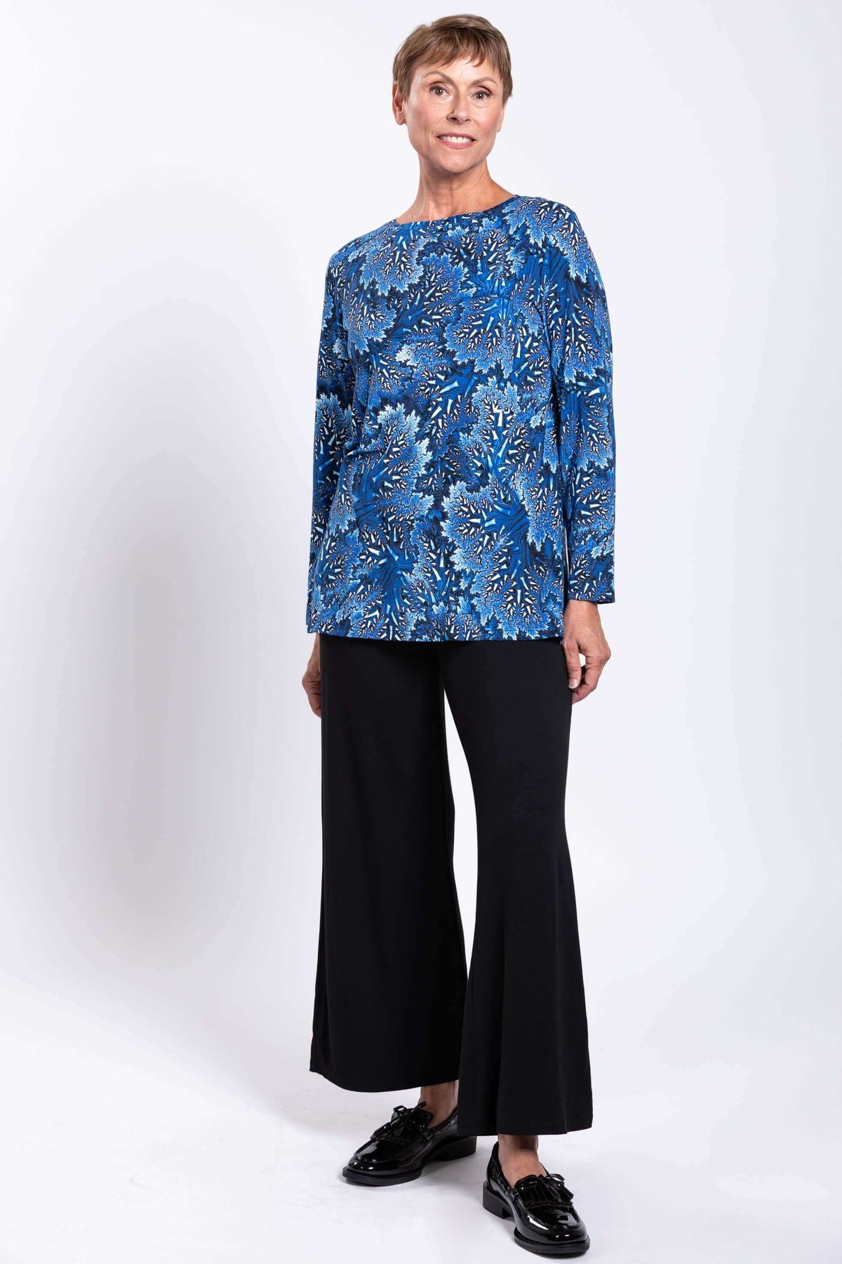 Full length portrait of a model showcasing a blue patterned tunic top with side leg slits.