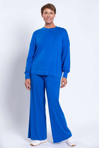 Woman standing in blue crew neck sweater and pants set, facing forward