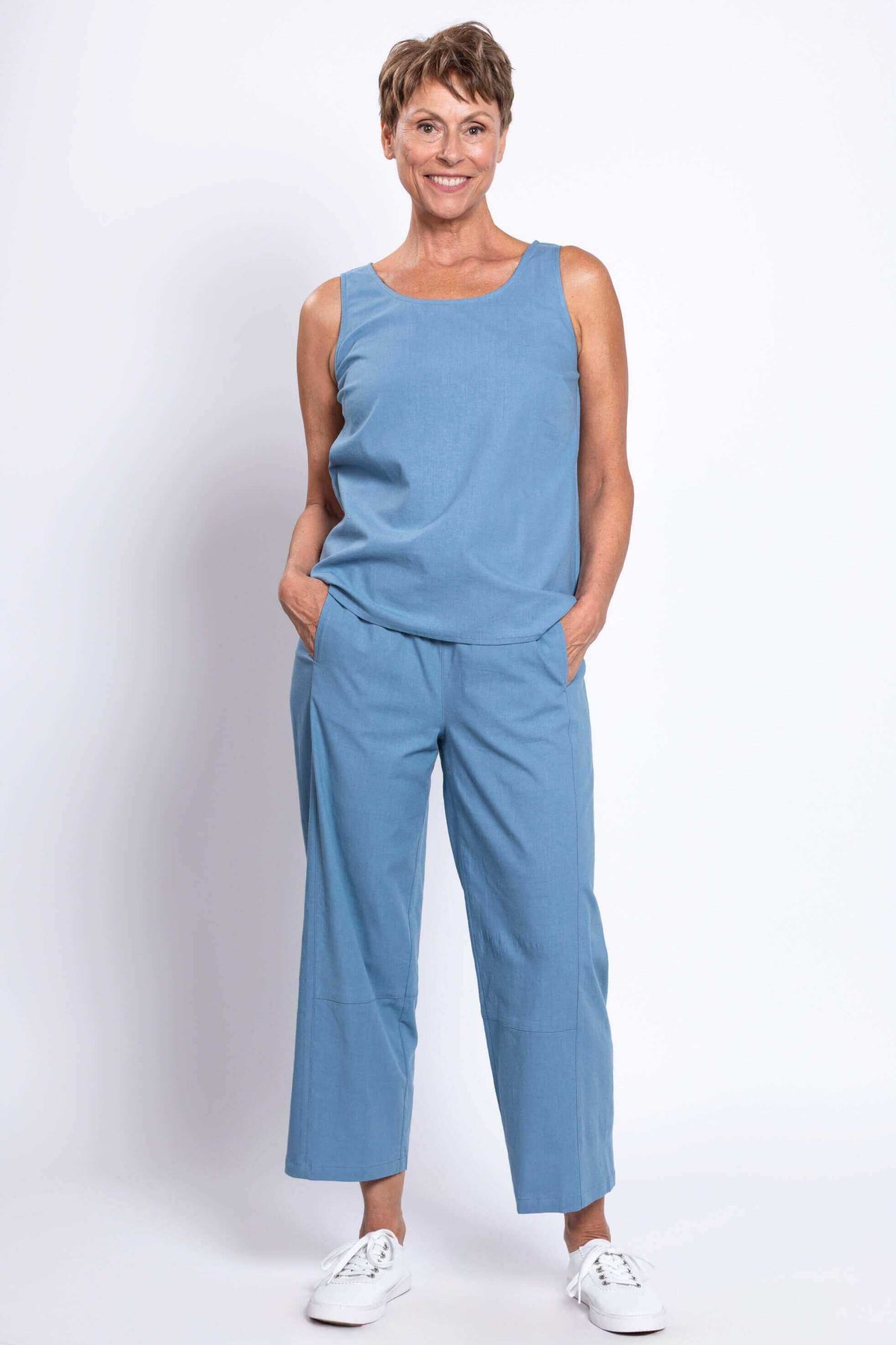 Woman wearing blue barrel-leg cropped pants and matching sleeveless top, front angled view
