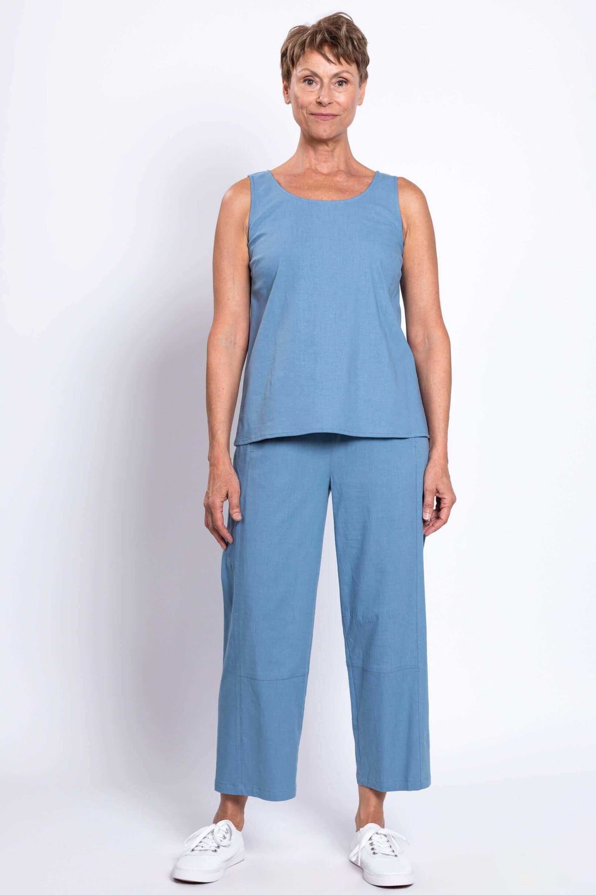 Woman wearing blue barrel-leg cropped pants and matching sleeveless top, front view