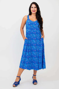 Woman wearing a sleeveless blue empire waist midi dress with floral print and side pockets