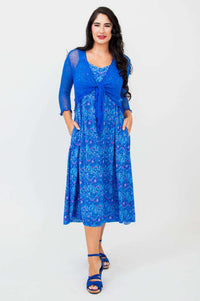 Woman modeling blue empire waist midi dress with lace shrug and pockets