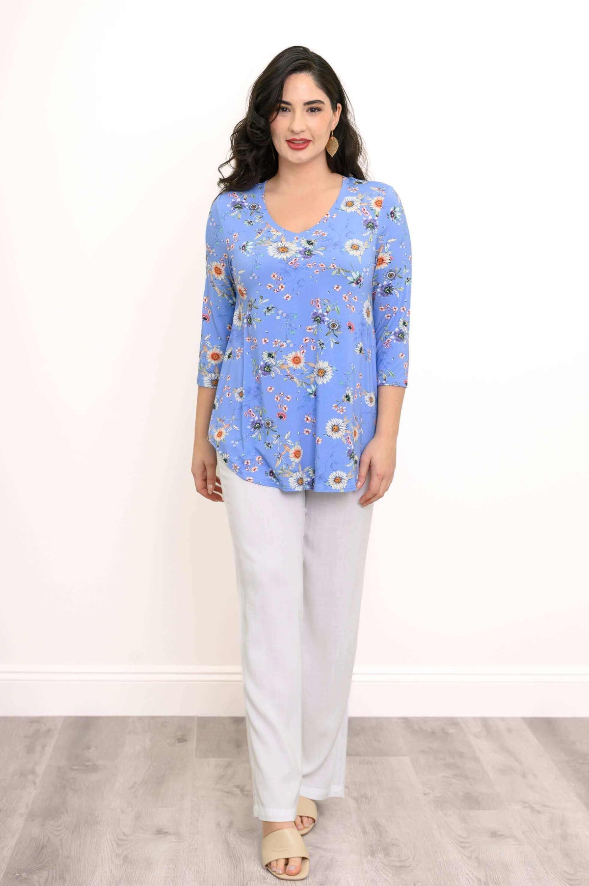 Woman in blue floral V-neck top and white pants, facing forward