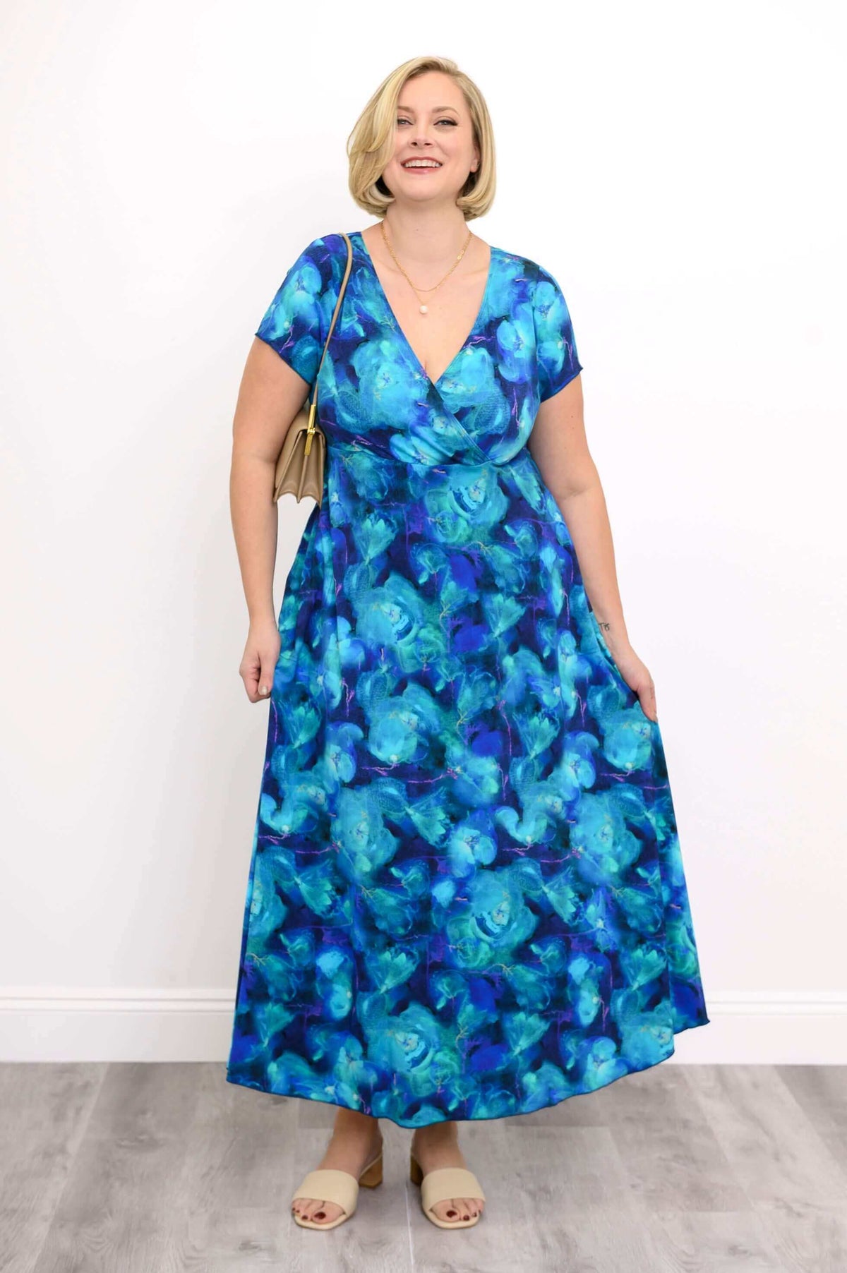 Woman smiling in a blue abstract print bamboo dress, hands resting on skirt pockets
