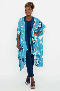 Woman in blue floral kimono wrap with hand on hip, looking to the side