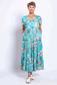 Woman with hands in pockets, wearing a blue floral linen maxi dress