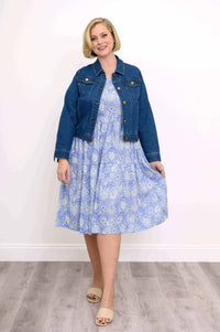Woman wearing a blue floral tiered dress with a cropped denim jacket and beige sandals