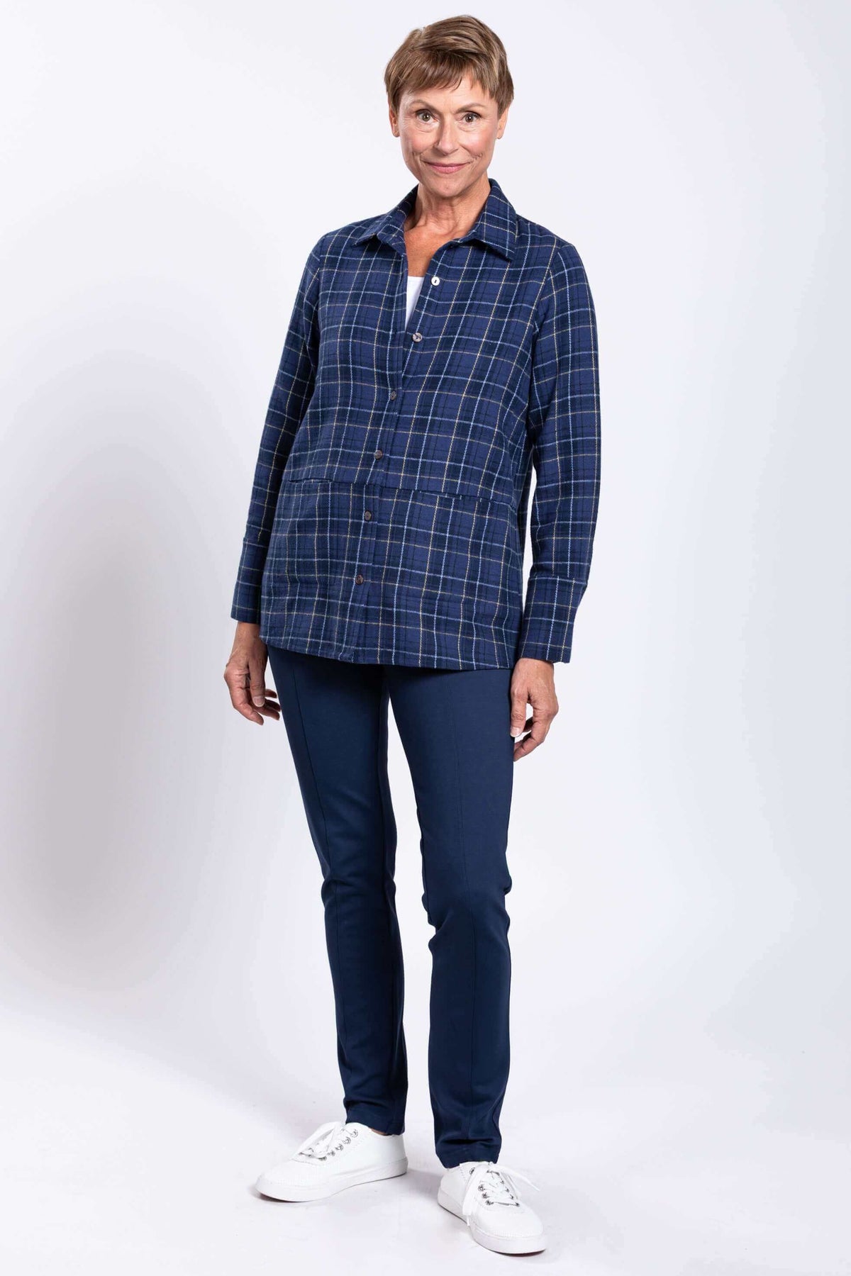 Woman standing in blue plaid jacket and navy pants, angled front view