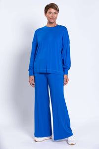 Woman in blue relaxed fit crew neck top and matching wide-leg pants, arms at sides