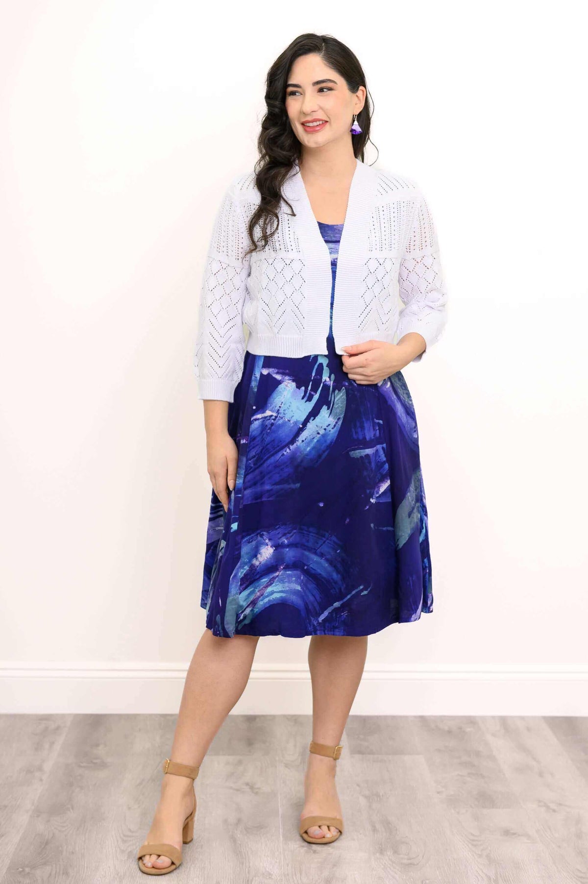 Woman in blue swirl print sleeveless dress with white knit cardigan