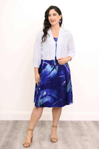 Woman in blue swirl print sleeveless dress with white knit cardigan