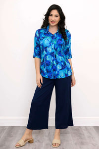 Woman in blue watercolor blouse and navy wide-leg pants, posing confidently