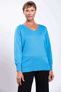 Woman wearing a bright blue V-neck sweater with ribbed cuffs and hem, front view close-up
