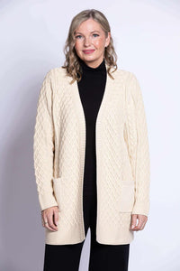 Woman wearing a cream cable knit cardigan with open front and front patch pockets