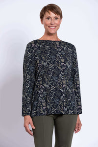 Woman wearing a dark floral print long sleeve top, facing forward with a smile