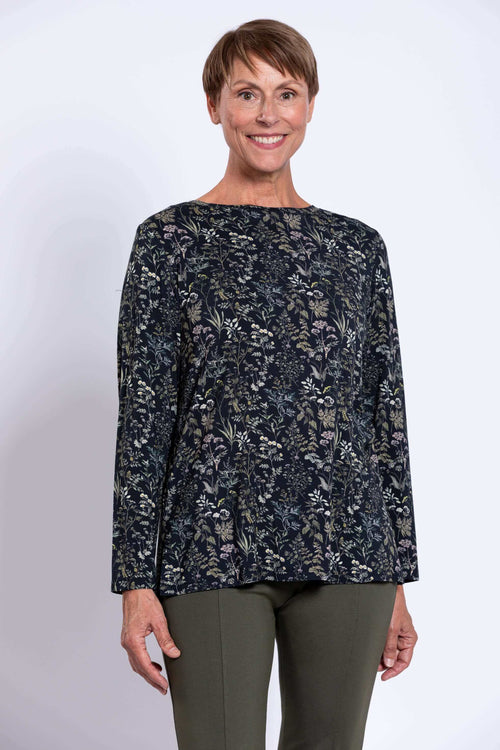 Woman wearing a dark floral print long sleeve top, facing forward with a smile