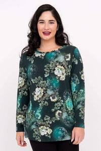 Woman in a dark green floral long sleeve tunic top standing and smiling