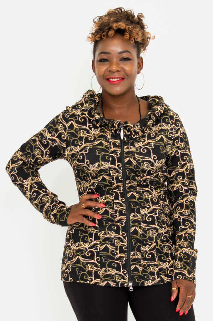 Woman wearing a fitted hooded jacket with gold vine print, zipped up