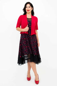 Woman in floral mesh dress with red shrug, facing forward