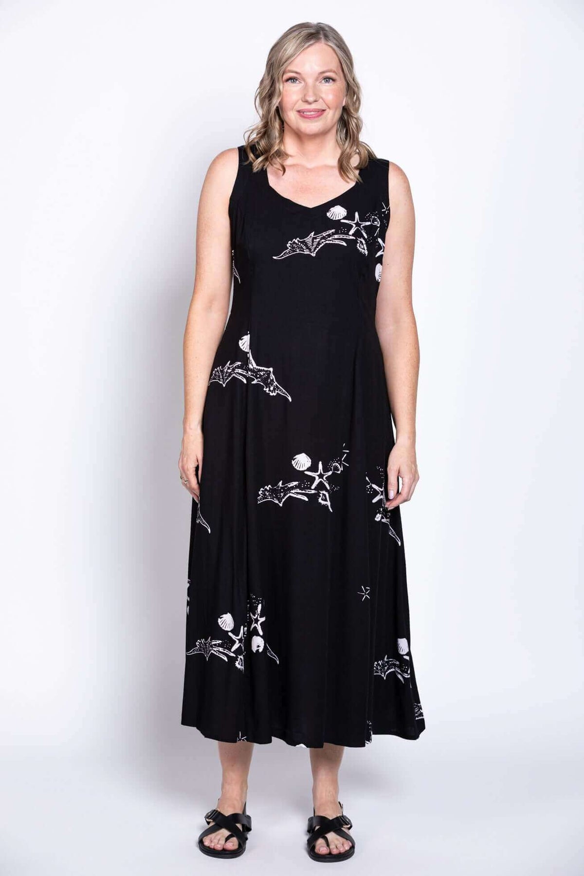 Full-body image of woman in a black A-line dress with unique white motifs