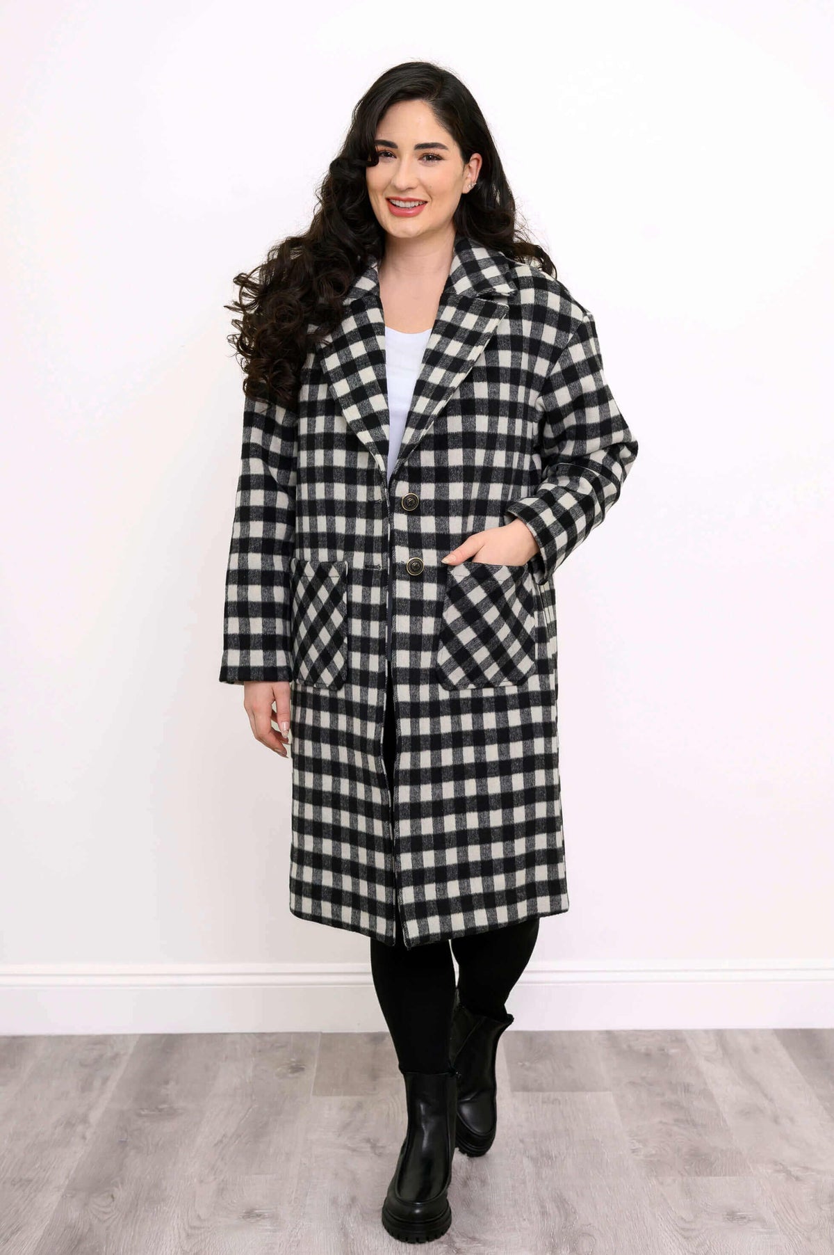 Woman facing forward in a black and white checkered long coat with button closure