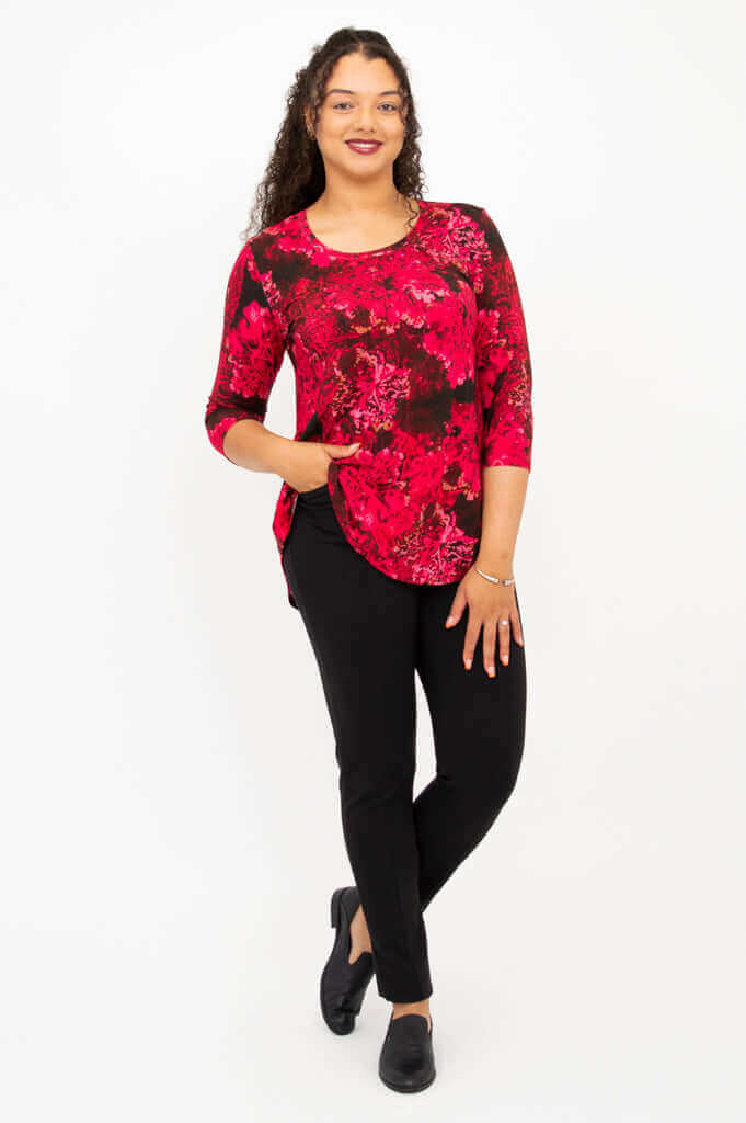 Woman in fuchsia swirl bamboo top with hand in pocket, standing confidently