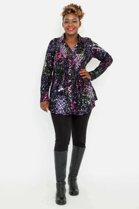Full body view of a woman in a colorful smocked tunic, black pants, and tall boots