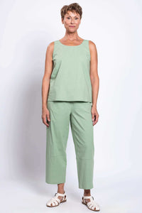 Woman standing in sleeveless green linen top and cropped boardwalk pants, facing forward