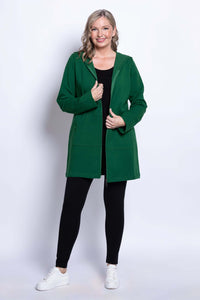 Woman smiling while wearing a green hooded jacket with zipper, black top, and leggings