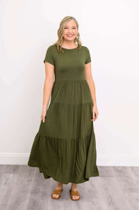 Woman in green maxi dress standing with brown sandals