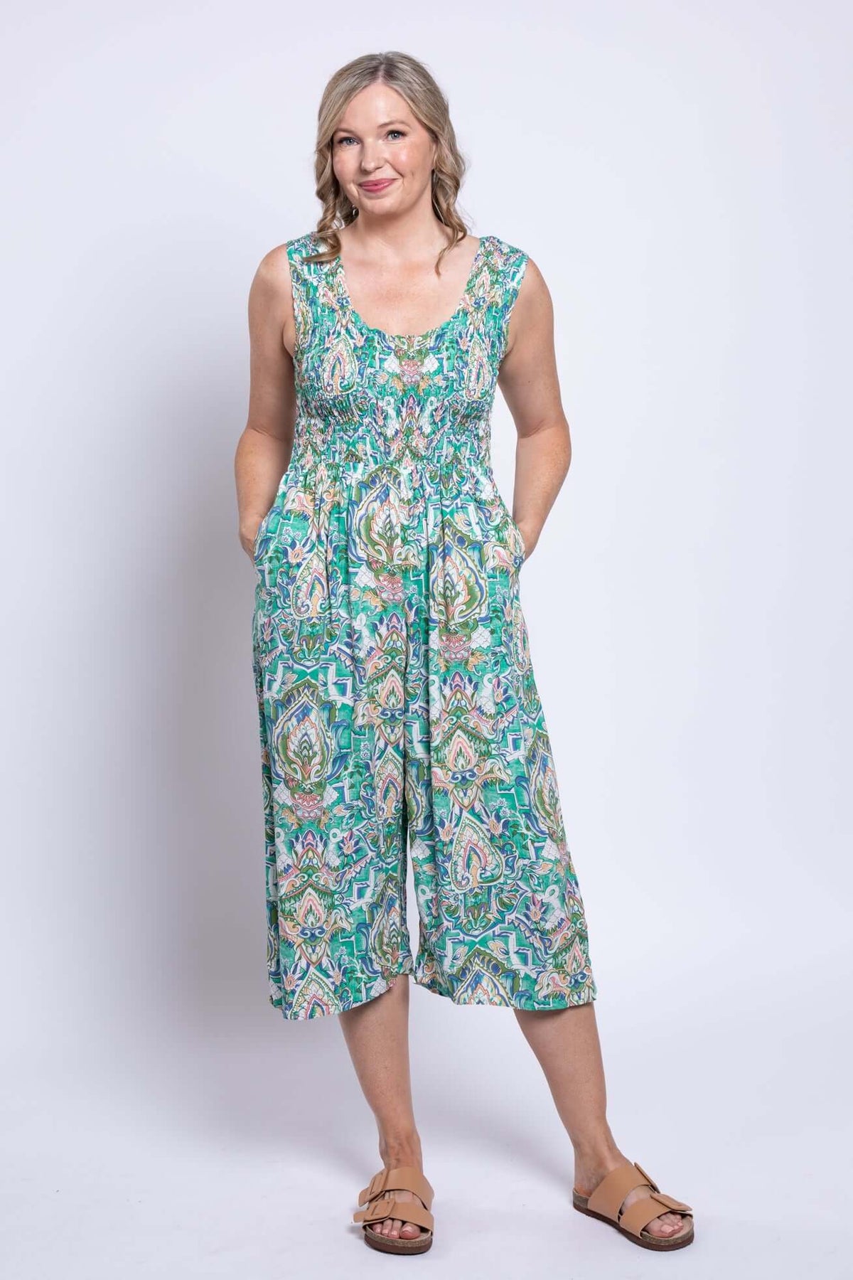 Woman wearing a green and paisley patterned jumpsuit with wide legs and side seam pockets