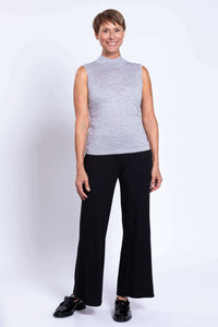 Woman wearing light grey sleeveless mock neck sweater and black wide-leg pants