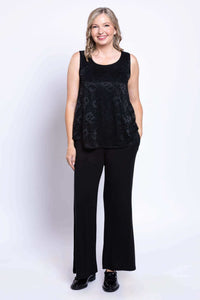 Woman standing and smiling in lace tank top and wide-leg black pants, front view