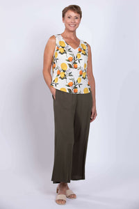 Woman posing in lemon print sleeveless V-neck tank top and green wide-leg pants