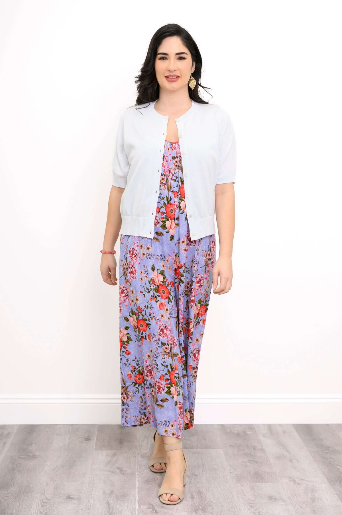 Woman in a light buttoned cardigan over a purple floral jumpsuit